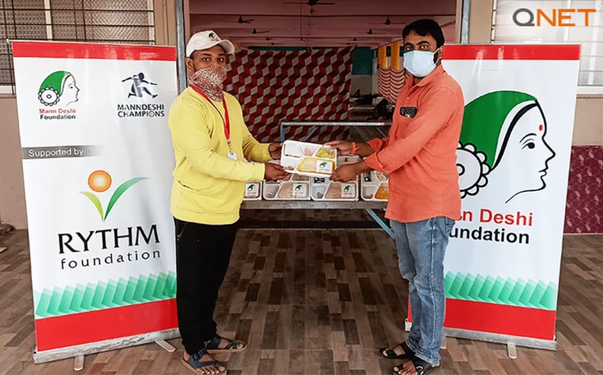 A representative from Mann Deshi Foundation providing meals to a beneficiary as a part of the COVID relief provided by QNET