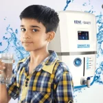 A small child drinking a glass of water with KENT RO in background