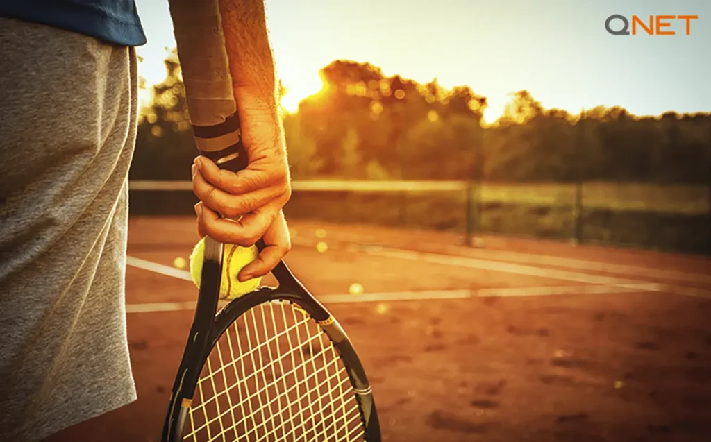A young man with a tennis racket in his hand about to step on the court