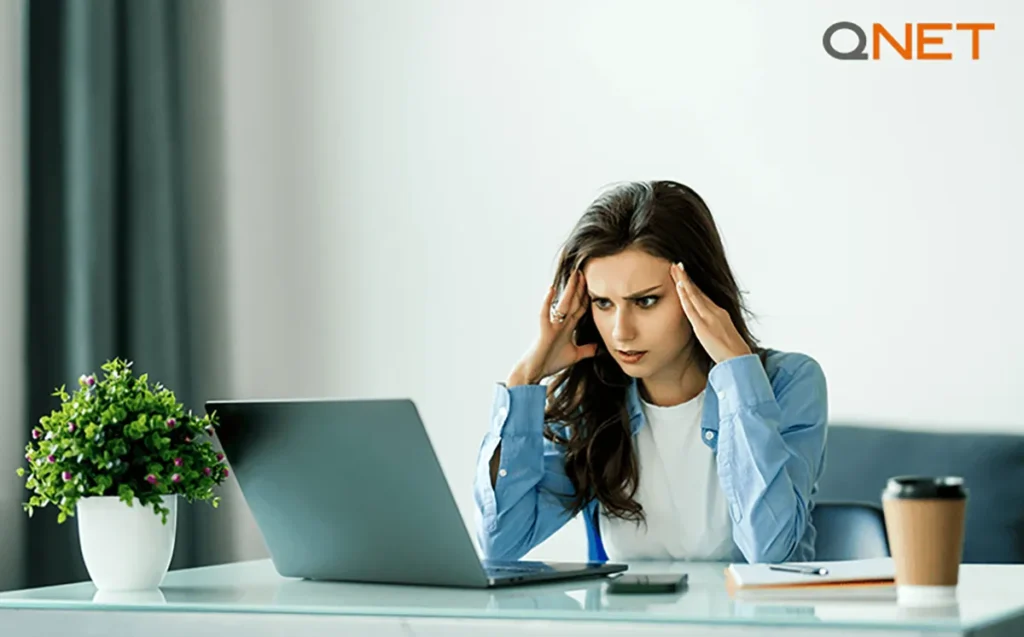 A stressed young woman holding her head | QNET India