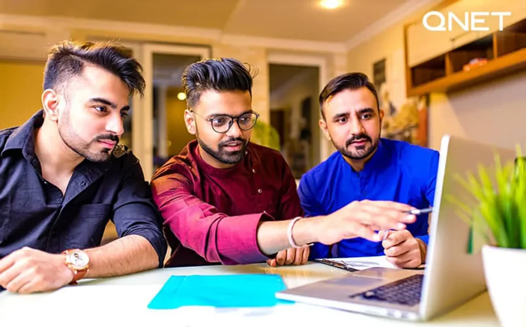 A team of men looking at the laptop screen together.