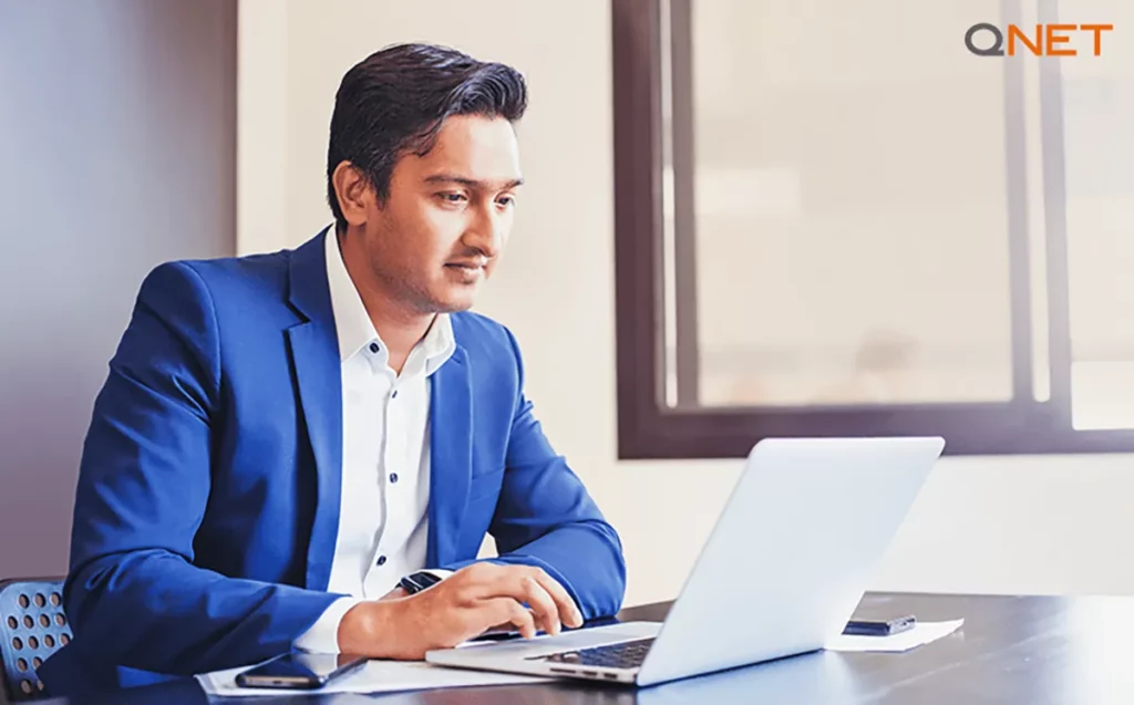Successful QNET India entrepreneur looking at his stats on a laptop in his office