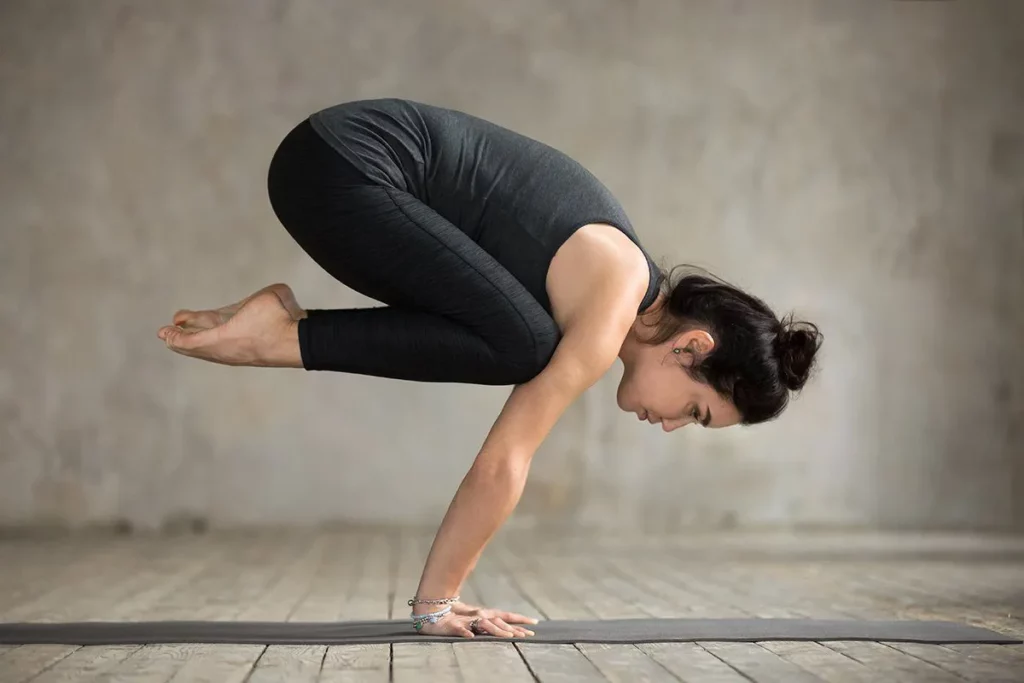 International Day of Yoga: young woman practising an arm balance exercise.